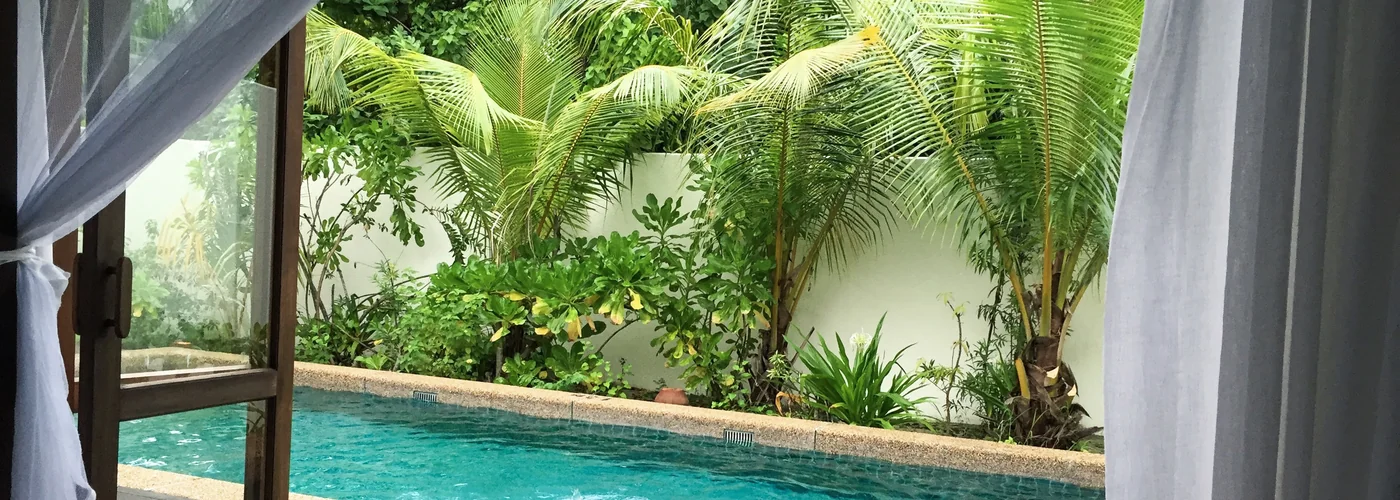 View from a tropical villa bedroom towards a private pool and garden