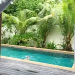 View from a tropical villa bedroom towards a private pool and garden