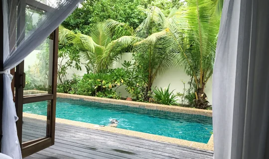 View from a tropical villa bedroom towards a private pool and garden